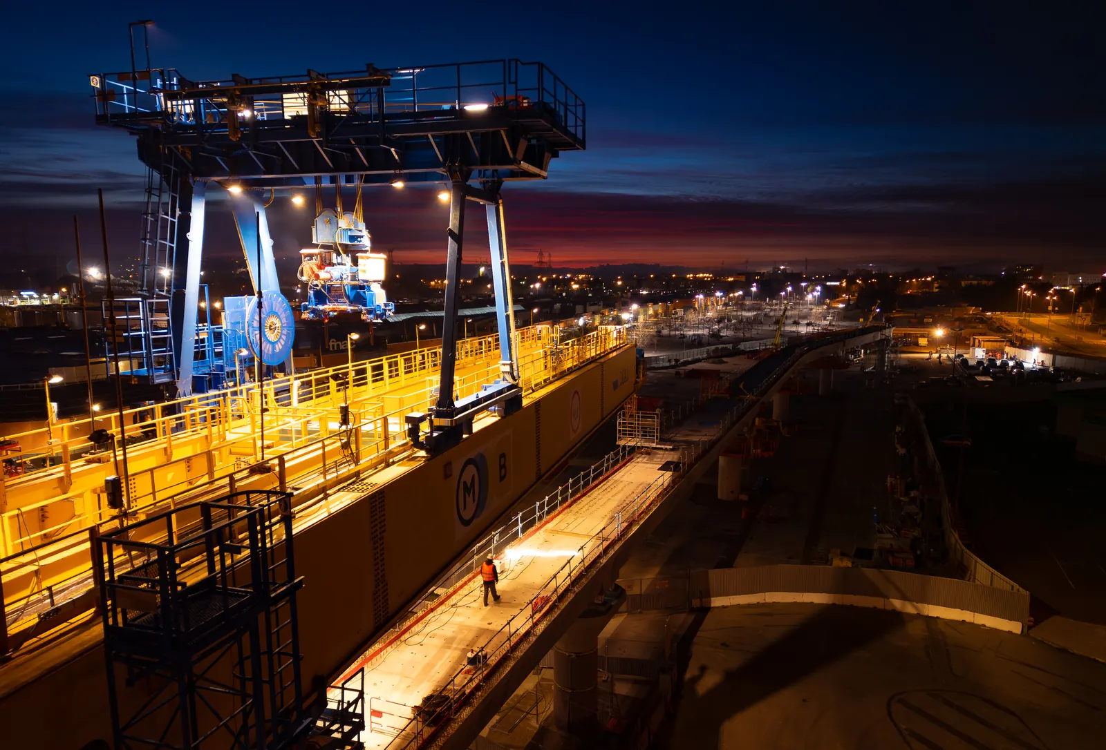 Gantry crane lit up on a construction site at dusk