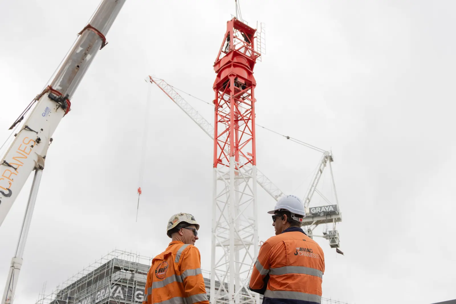 Two workers watching a tower crane go up